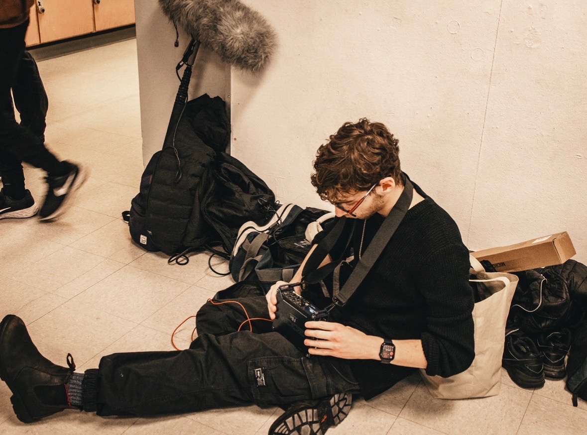 Costa seated behind the scenes organizing audio equipment